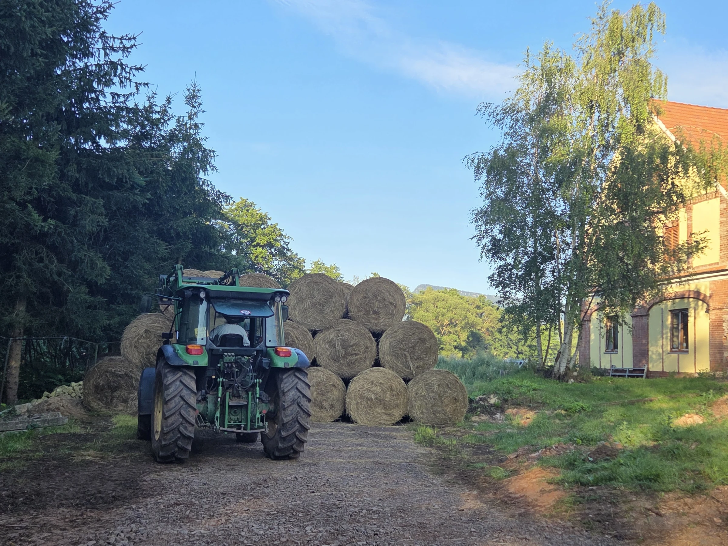 Traktor před balíky sena na dvoře farmy
